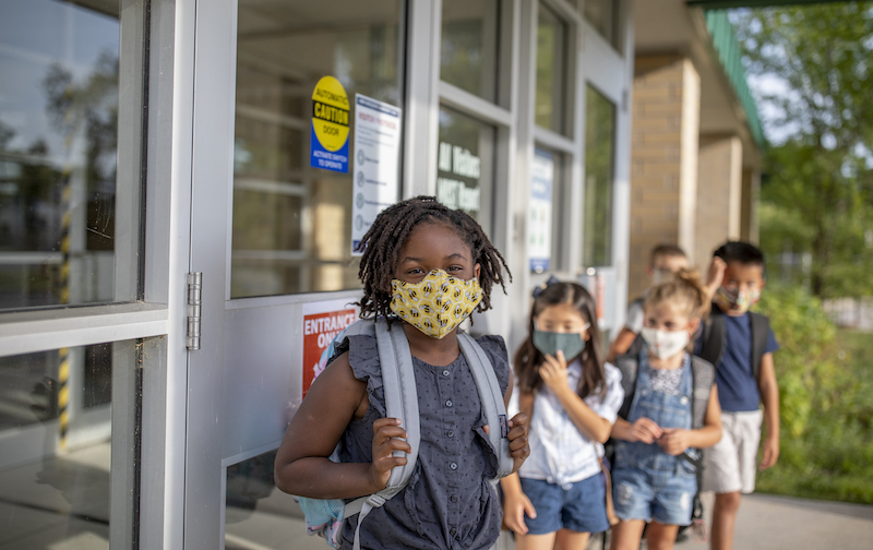 Diverse Group Of Elementary School Kids Go Back To School Wearing Masks