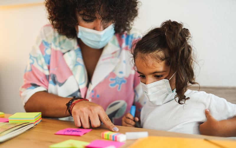 Mother Doing Home Schooling With Child While Wearing Surgical Face Mask For Coronavirus