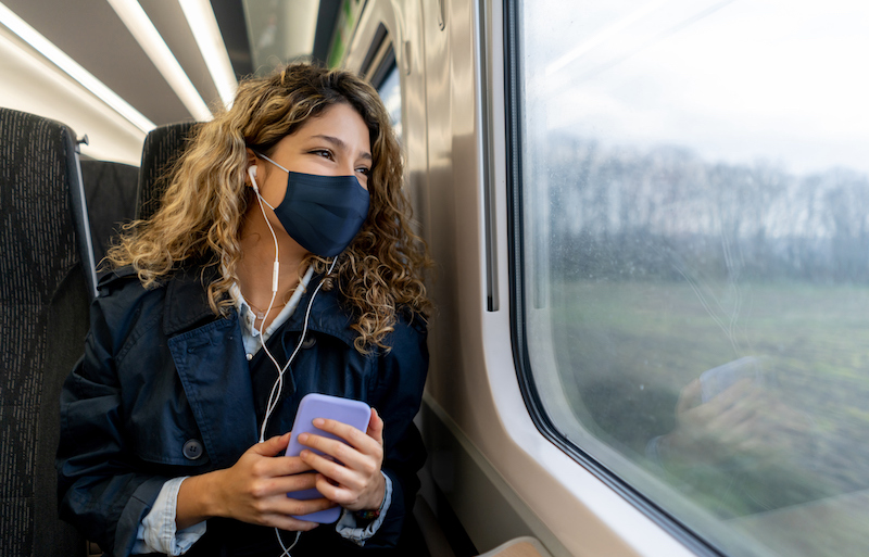 Happy Woman Traveling By Train Wearing A Facemask