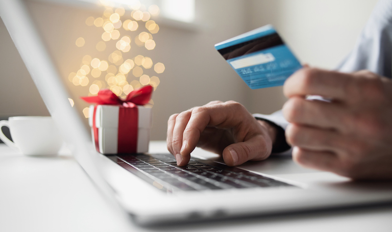 Online Shopping During Holidays. Man Ordering Christmas Gift Using Laptop And Credit Card