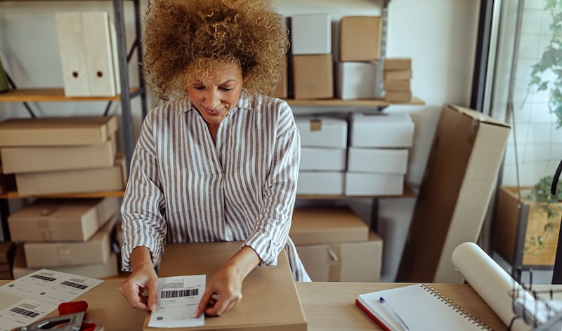 Businesswoman Sticking Bar Code Label On Delivery Package