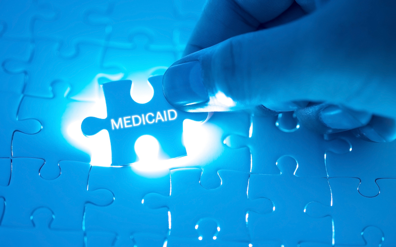 Health Care Concept. Doctor Holding A Jigsaw Puzzle With Medicaid Word.
