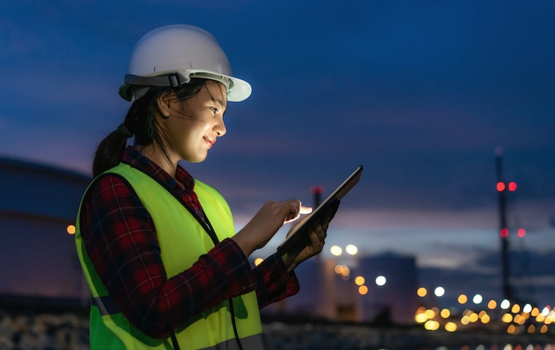 Asian Woman Petrochemical Engineer Working At Night With Digital Tablet Inside Oil And Gas Refinery Plant Industry Factory At Night For Inspector Safety Quality Control.