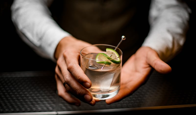 Close Up On Hands Of Man Bartender Holding Glass With Cold Drink