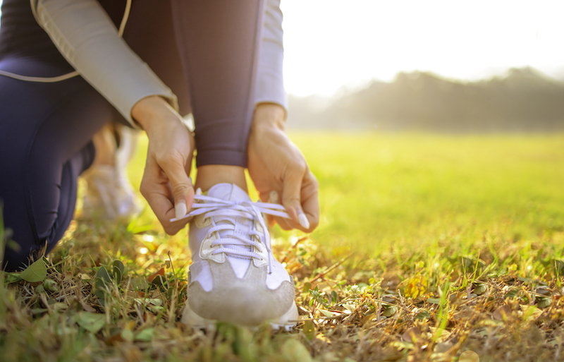 Young Woman Runner Tying Her Shoes Preparing For A Jog Outside At Morning