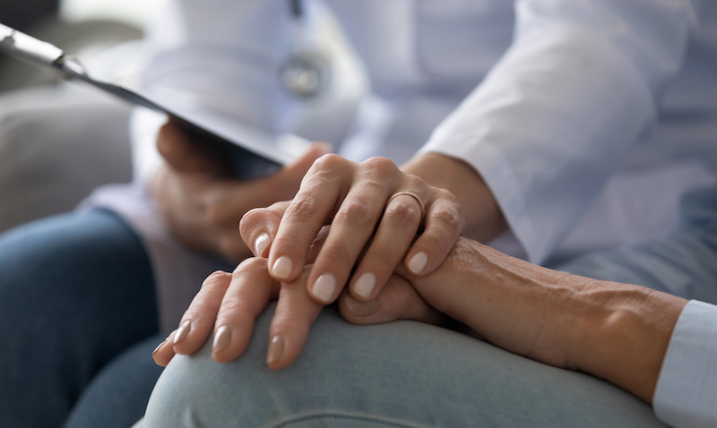 Young Woman Doctor Holding Hand Of Senior Grandmother Patient, Closeup