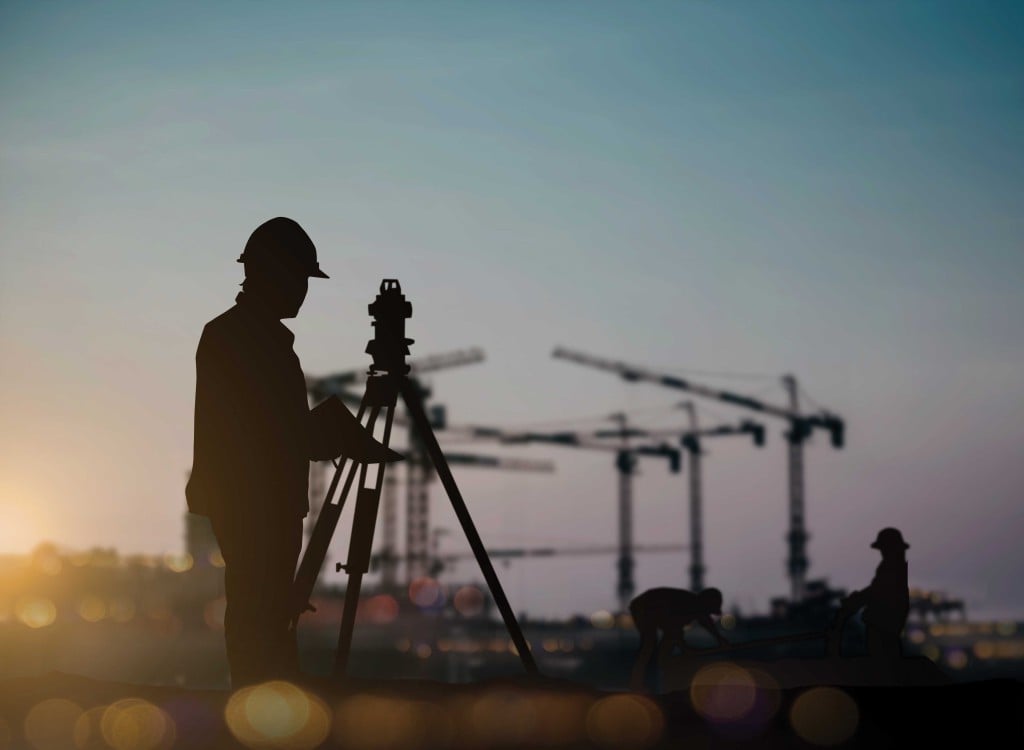 Silhouette Engineer Looking Loaders And Trucks In A Building Site Over Blurred Construction Worker On Construction Site