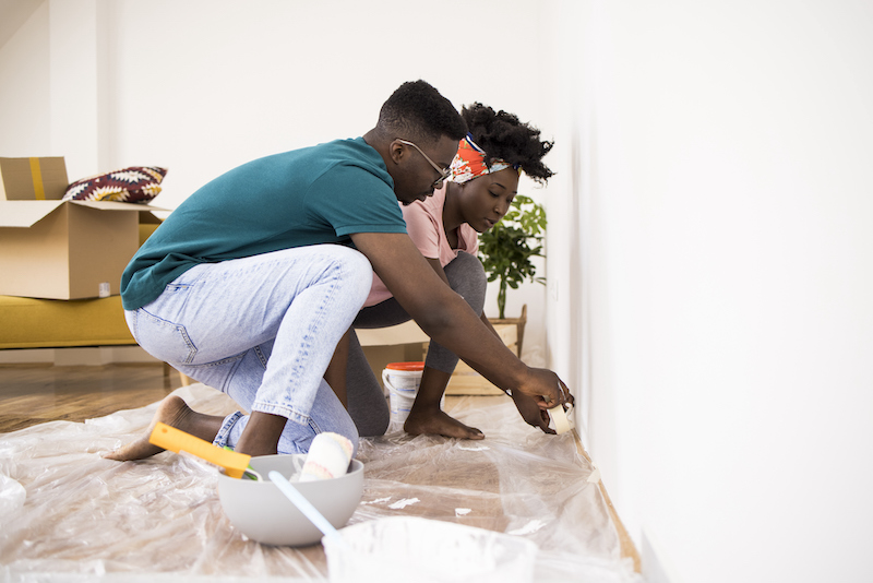 Husband Helping Wife While Painting Apartment Together
