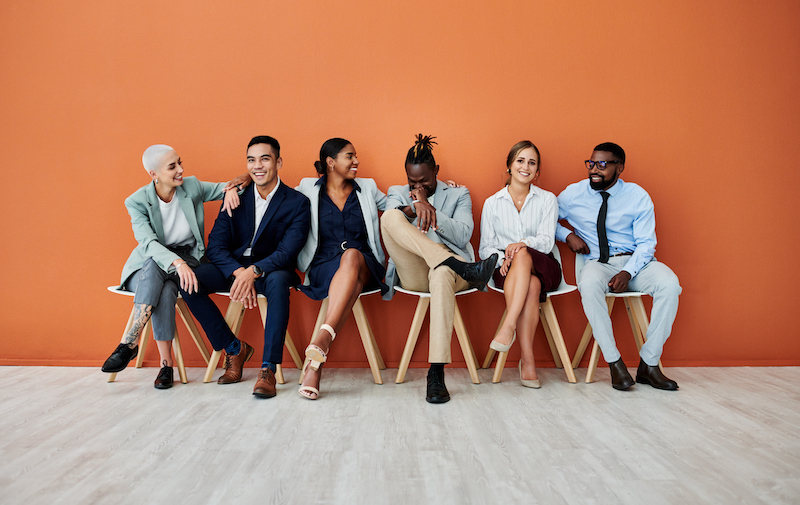 Shot Of A Group Of Businesspeople Sitting Against An Orange Background