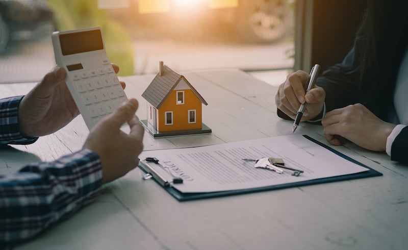 Real Estate Professionals Offer Their Clients Contracts To Discuss Home Purchases, Insurance Or Real Estate Loans. Home Sales Agents Sit At The Office With New Home Buyers In The Office.