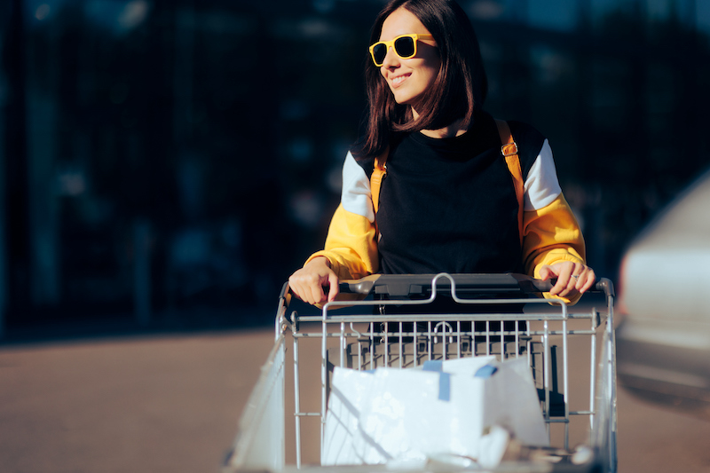 Cheerful Woman Wearing Sunglasses Pushing A Shopping Cart