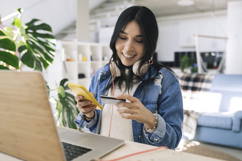 Pretty Hispanic Woman Doing Online Shopping At Home With Credit Card And Smartphone