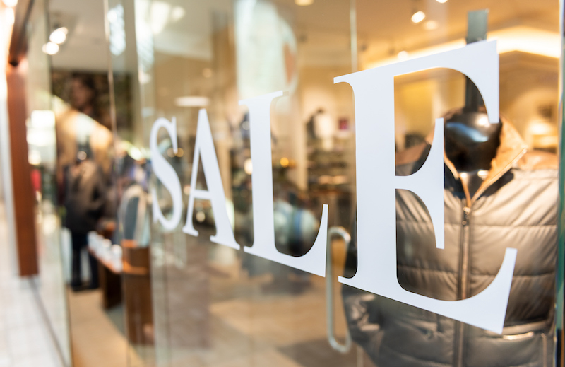 Closeup Of Sale Sign On Clothes, Clothing, Apparel Retail Store, Shop Window In Shopping Mall