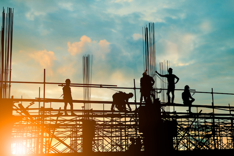 Silhouette Of Engineer And Construction Team Working Safely On Scaffolding On High Rise Building. Over Blurred Background Sunset Pastel For Industry Background With Light Fair