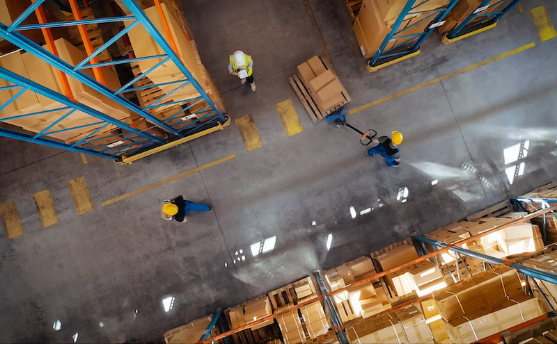 Top Down View: In Warehouse People Working, Forklift Truck Operator Lifts Pallet With Cardboard Box. Logistics, Distribution Center With Products Ready For Global Shipment, Customer Delivery