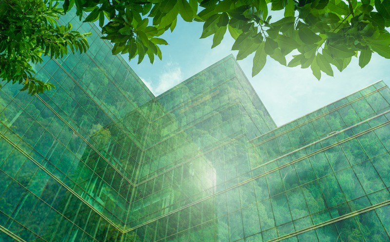 Eco Friendly Building In The Modern City. Sustainable Glass Office Building With Tree For Reducing Heat And Carbon Dioxide. Office Building With Green Environment. Corporate Building Reduce Co2.