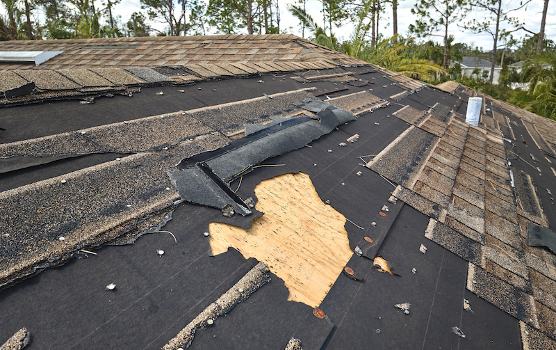 Damaged House Roof With Missing Shingles After Hurricane Ian In Florida. Consequences Of Natural Disaster