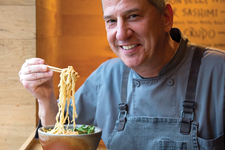 Man in apron making spaghetti with noodle cutter. Close-up pasta