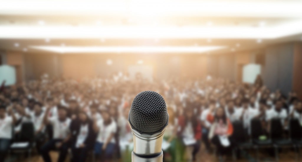 Microphone,over,the,abstract,blurred,photo,of,conference,hall,or
