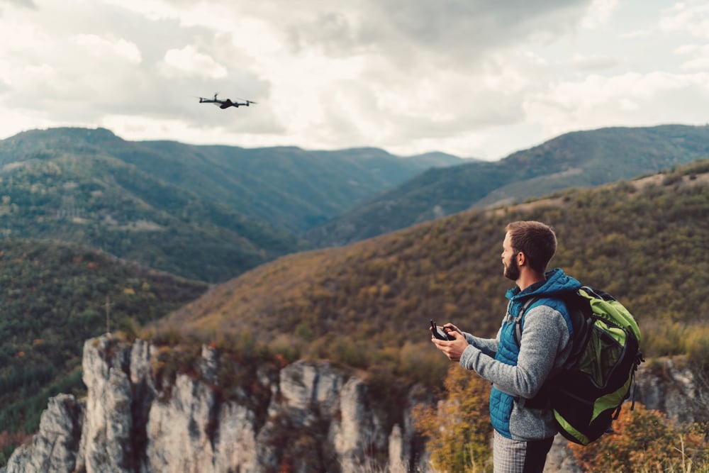 Hiker On The Mountain Top Flying A Drone To Make Videos And Photos