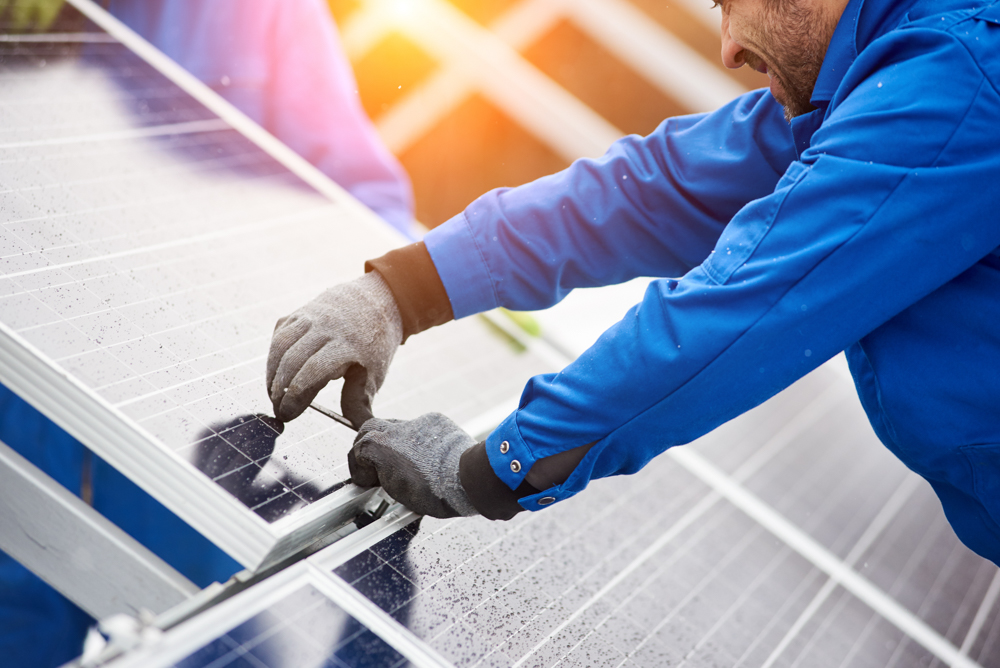 Smiling,male,technician,in,blue,suit,installing,photovoltaic,blue,solar