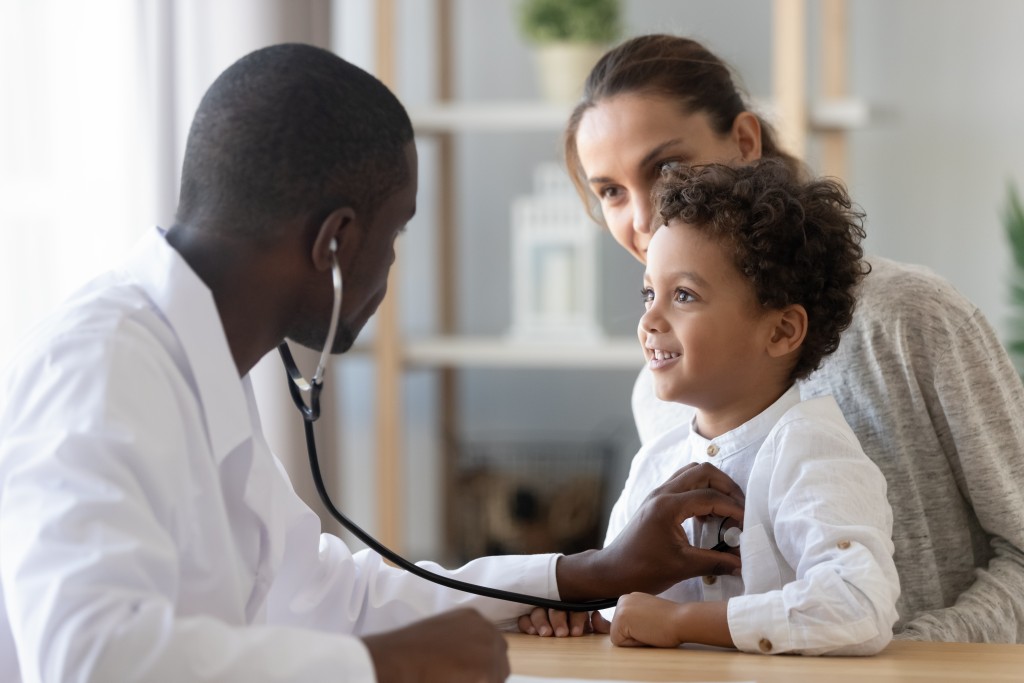 African,american,male,pediatrician,with,stethoscope,listening,to,lung,and