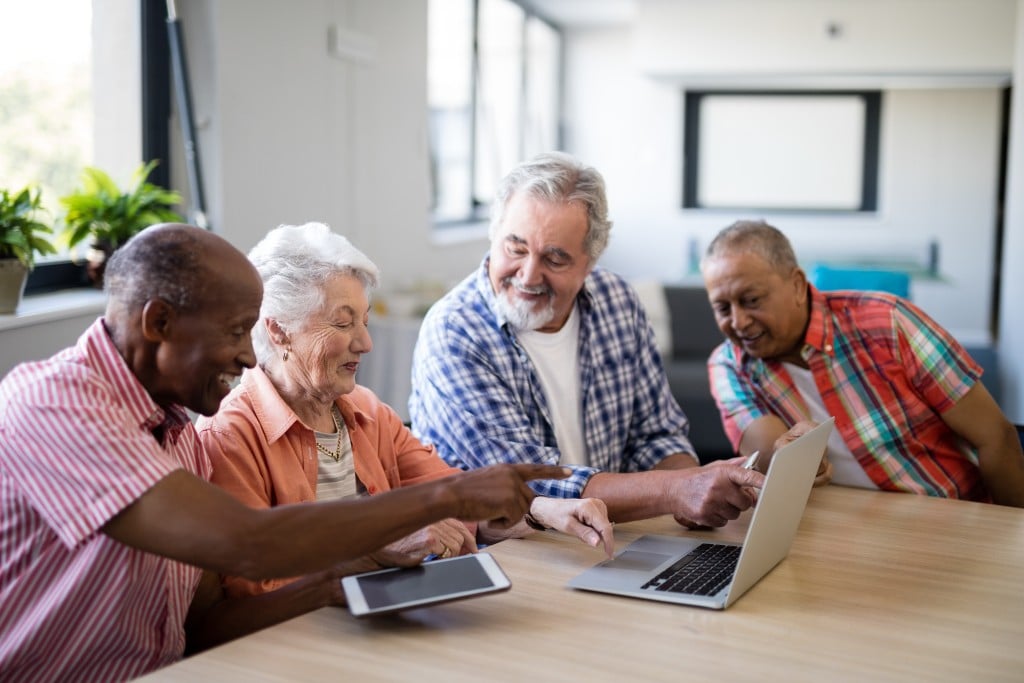 Happy,senior,men,and,woman,using,laptop,while,sitting,at