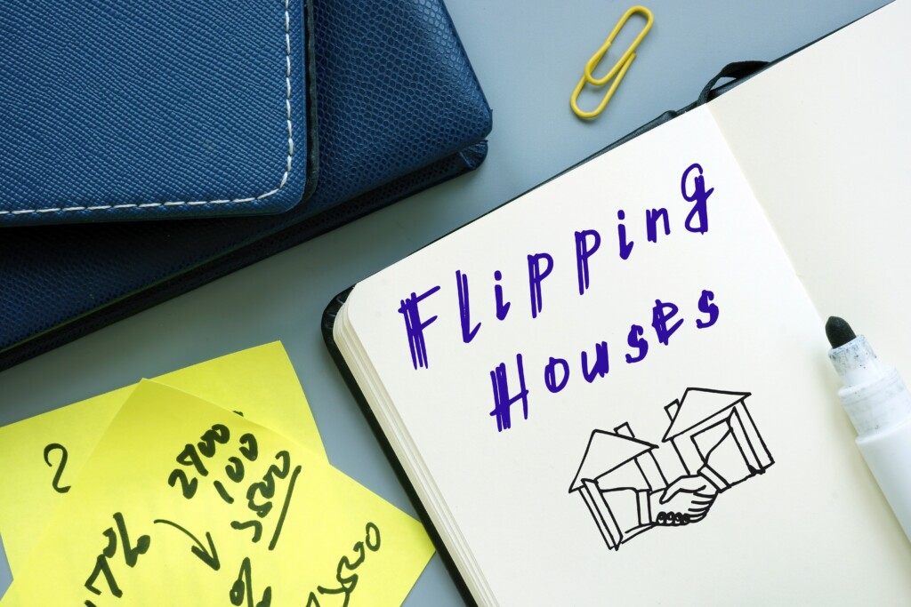 Residential real estate flipping concept: Flipping Houses Phrase written on paper notebook Page.