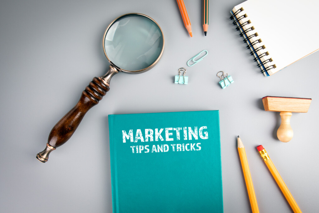 Marketing, Tips And Tricks. Green Book Cover And Magnifying Glass