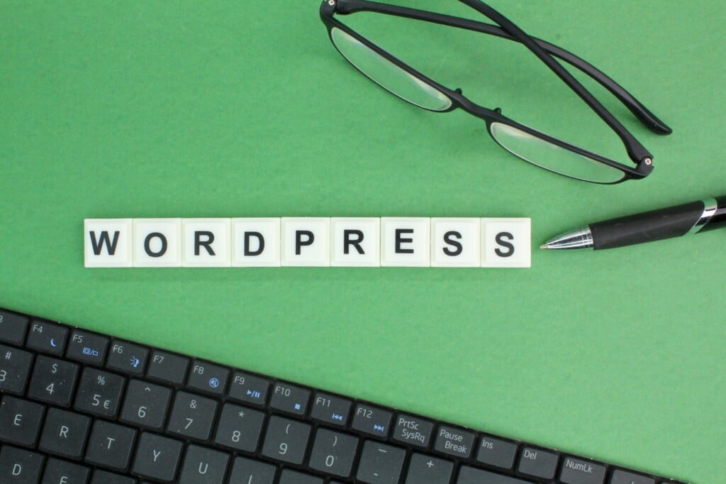 WordPress Accessibility Concept: laptop keyboard, glasses and pen with WordPress alphabet words.