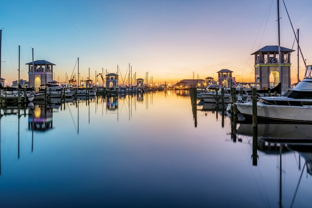 Railing Draped In Fishing Net On Dock With Boat Stock Photo