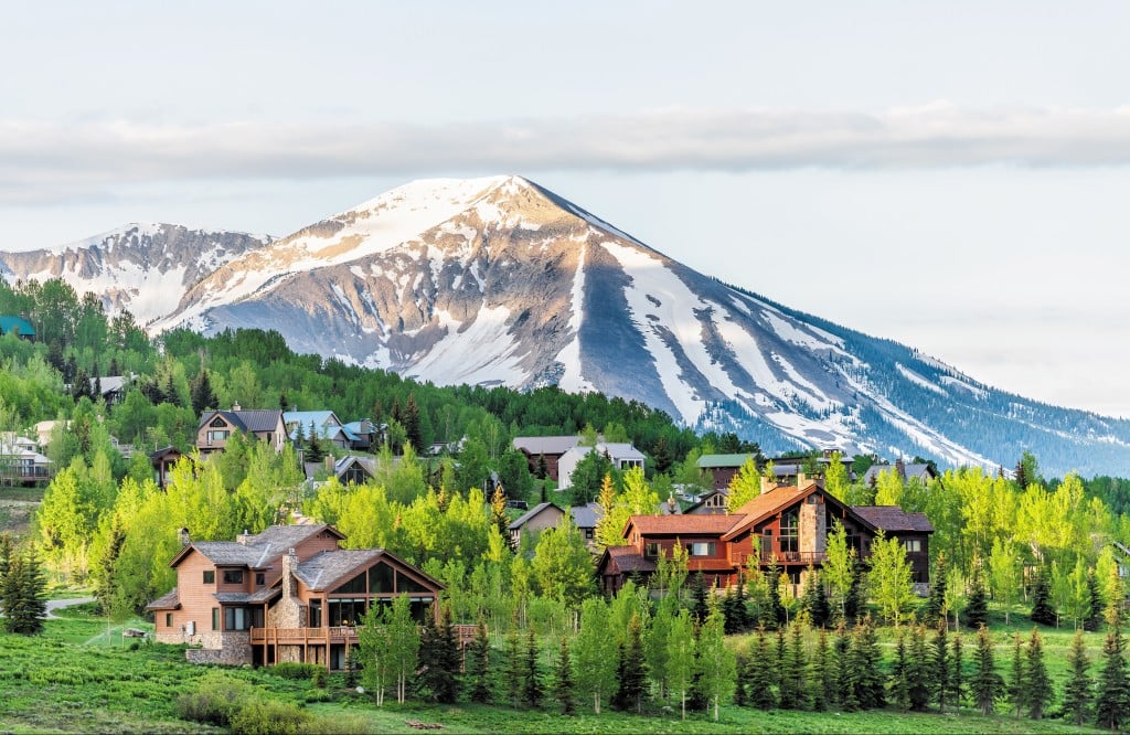 Mount Crested Butte, Colorado Village In Summer With Colorful Sunrise By Wooden Lodging Houses On Hills With Green Trees