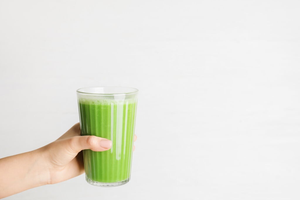Woman Holding Glass Of Tasty Green Smoothie On Light Background