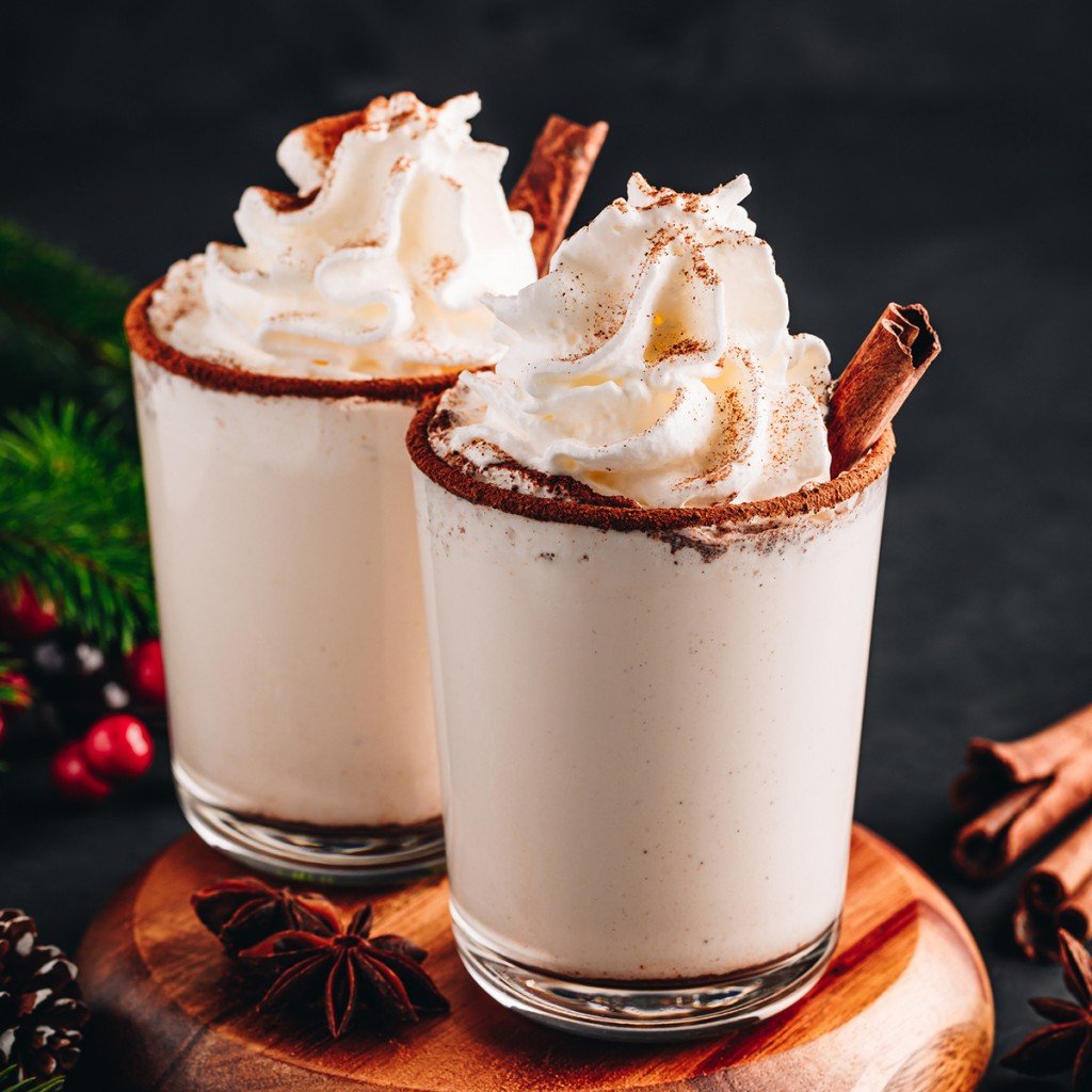 Traditional Christmas Drink Eggnog With Whipped Cream And Cinnamon On Dark Stone Background.