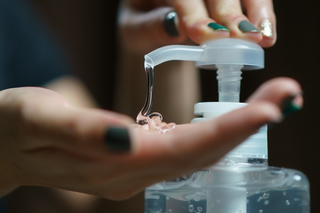 Hands Using Wash Hand Sanitizer Gel Pump Dispenser. Clear Sanitizer In Pump Bottle, For Killing Germs, Bacteria And Virus.