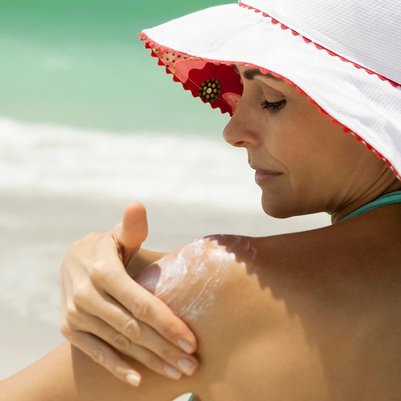 Woman At The Beach Applying Sunscreen