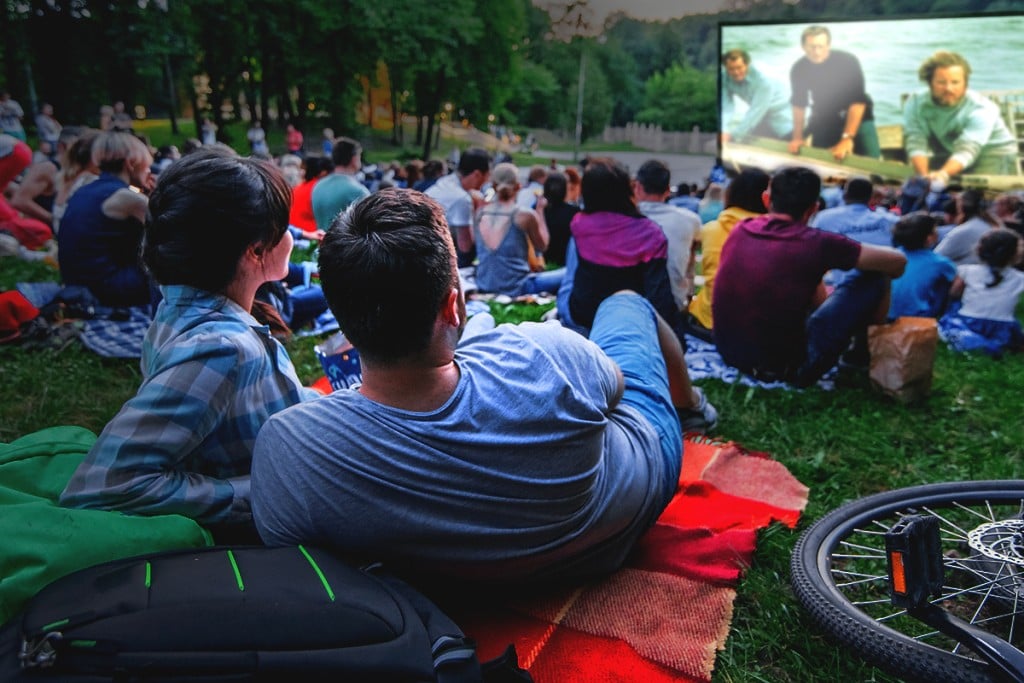 People Watching Movie In Open Air Cinema In City Park