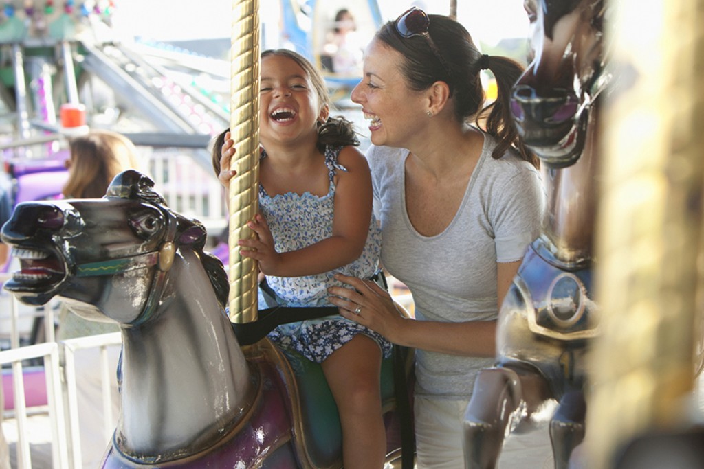 Hispanic Mother And Daughter Riding Carousel