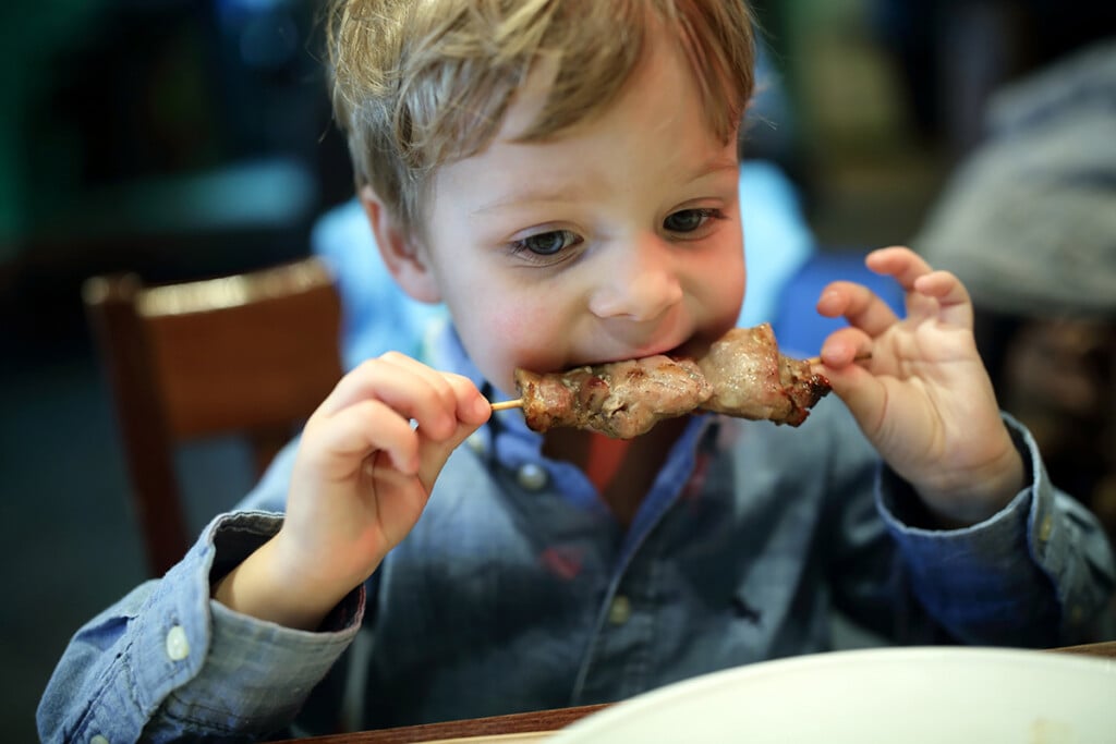 Child,biting,kebab,in,an,asian,restaurant
