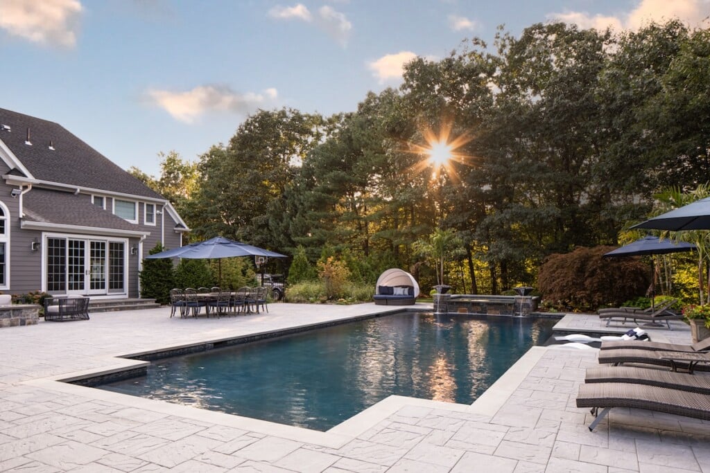 Photo of a beautiful house with a pool surrounded by trees.