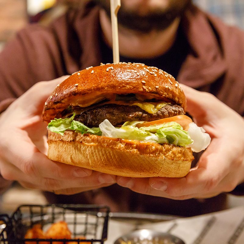 Unhealthy Food, High Fat And Carbs Burger In The Hand