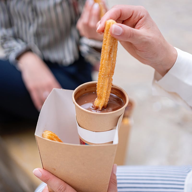 Hands dipping a pastry in chocolate