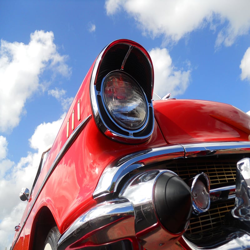 Photo of the headlight of a 1950s Chevy car painted red.