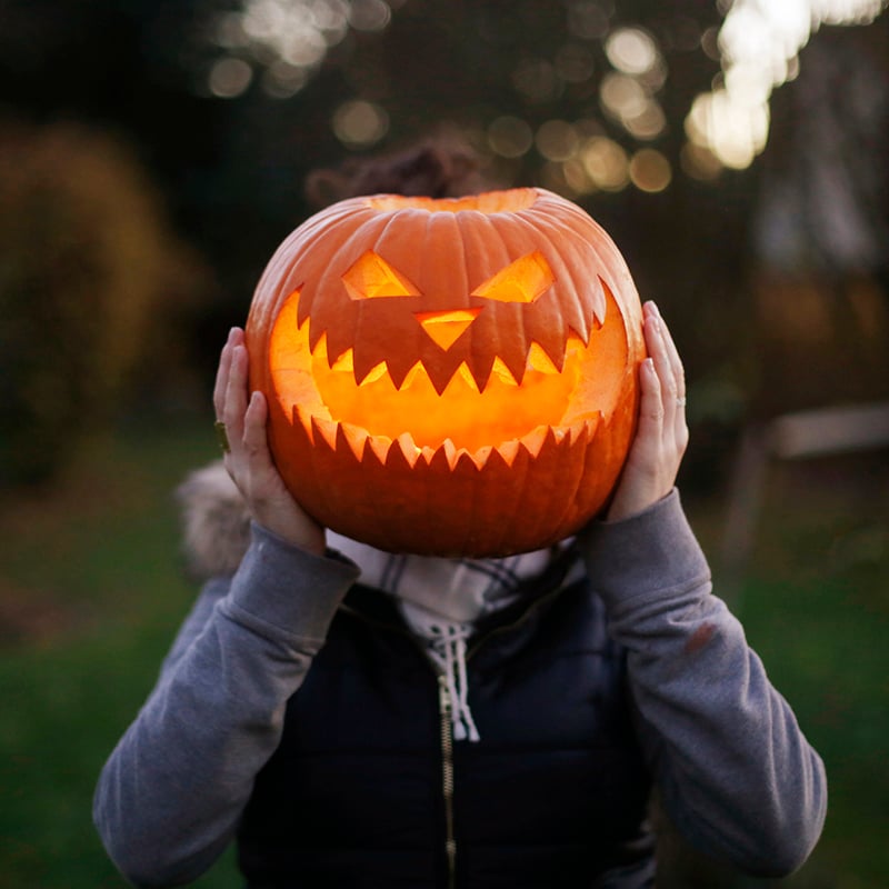 A Girl With Halloween Pumpkin In Front Of Her Head