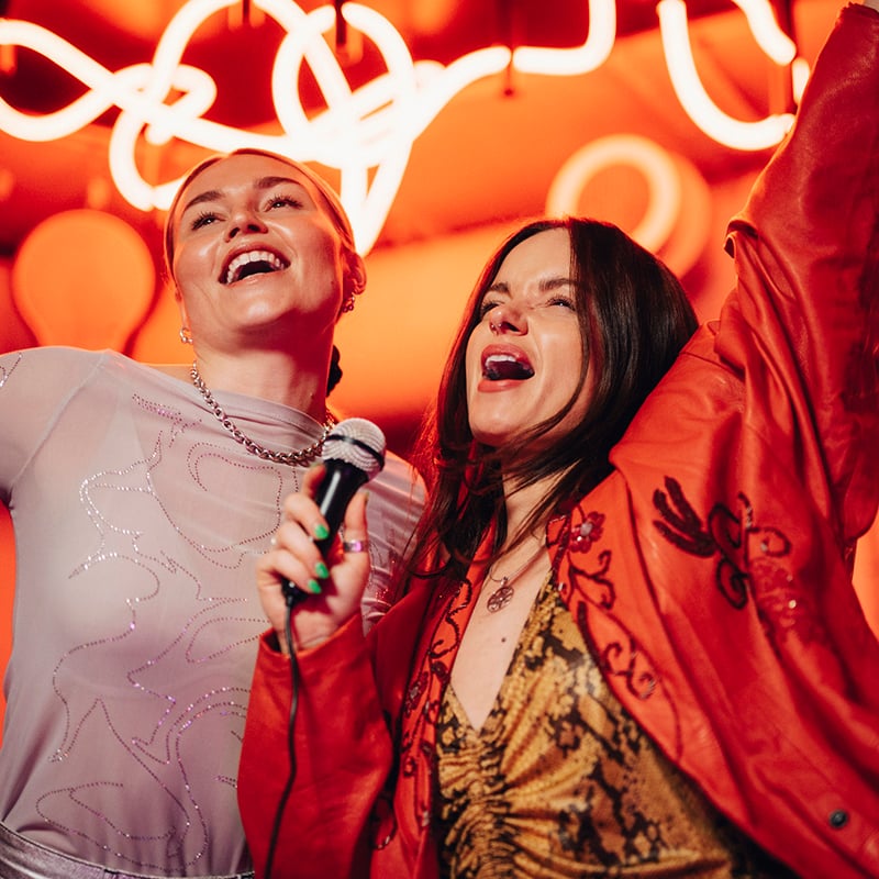Carefree Female Friends Singing Karaoke And Enjoying At Nightclub