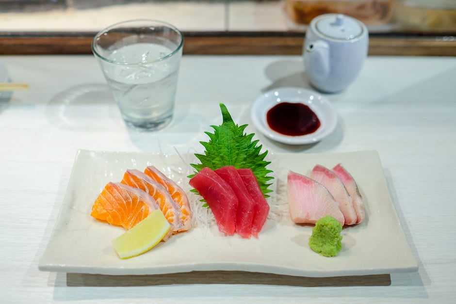 Assorted happy hour sashimi plate with a glass of shochu.
