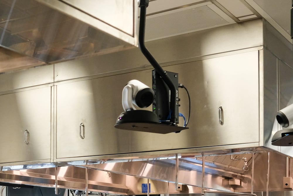 Cameras are mounted above the lab floor to capture a high angle view of students or instructors demonstrating their work. 