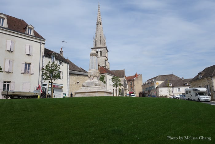 A war monument in the middle of Meursault, with the church behind it.
