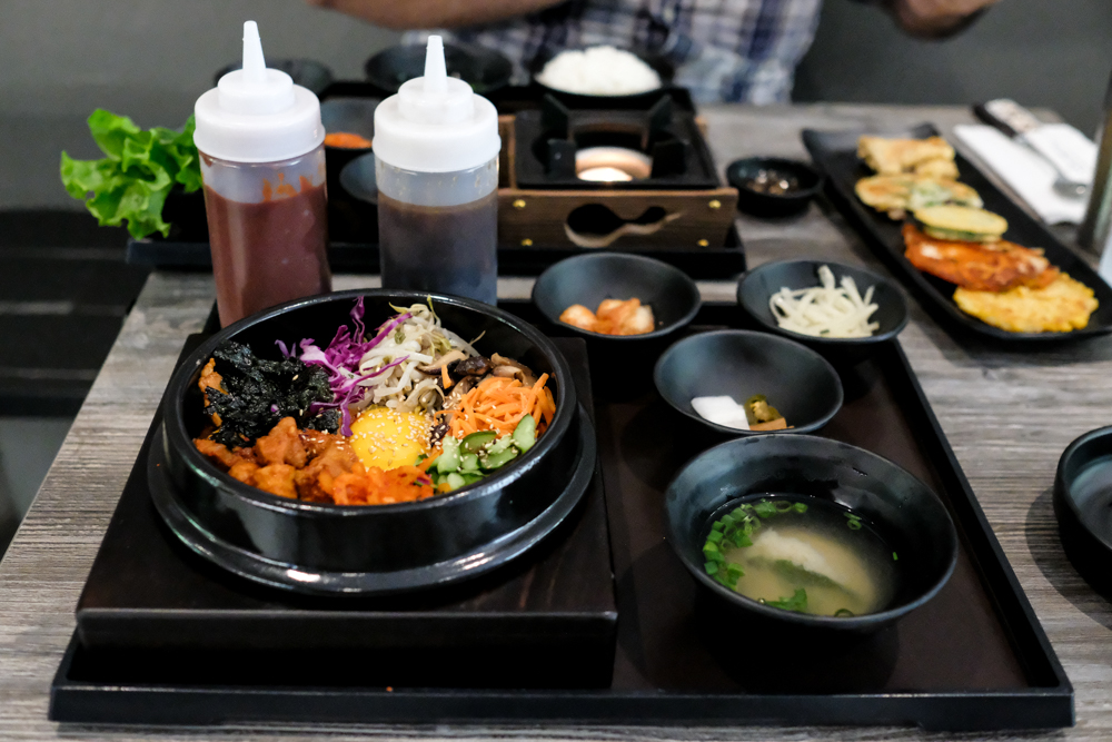 The bi bim bap arrives on a hefty tray with enormous bottles of gochujang and ganjang sauces, a few banchan and miso soup. 