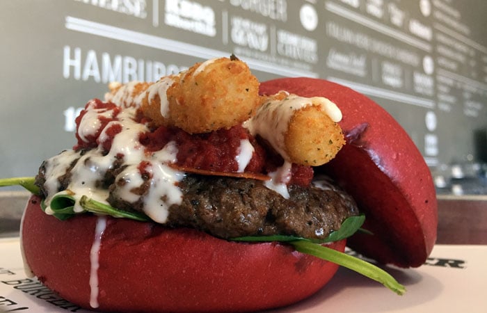 The Italian Stallion encompasses a burger topped with two mozzarella sticks, pepperoni, spinach, pizza sauce and Ranch dressing in between two spongy, fresh, raspberry-infused buns. Hence the reddish color.